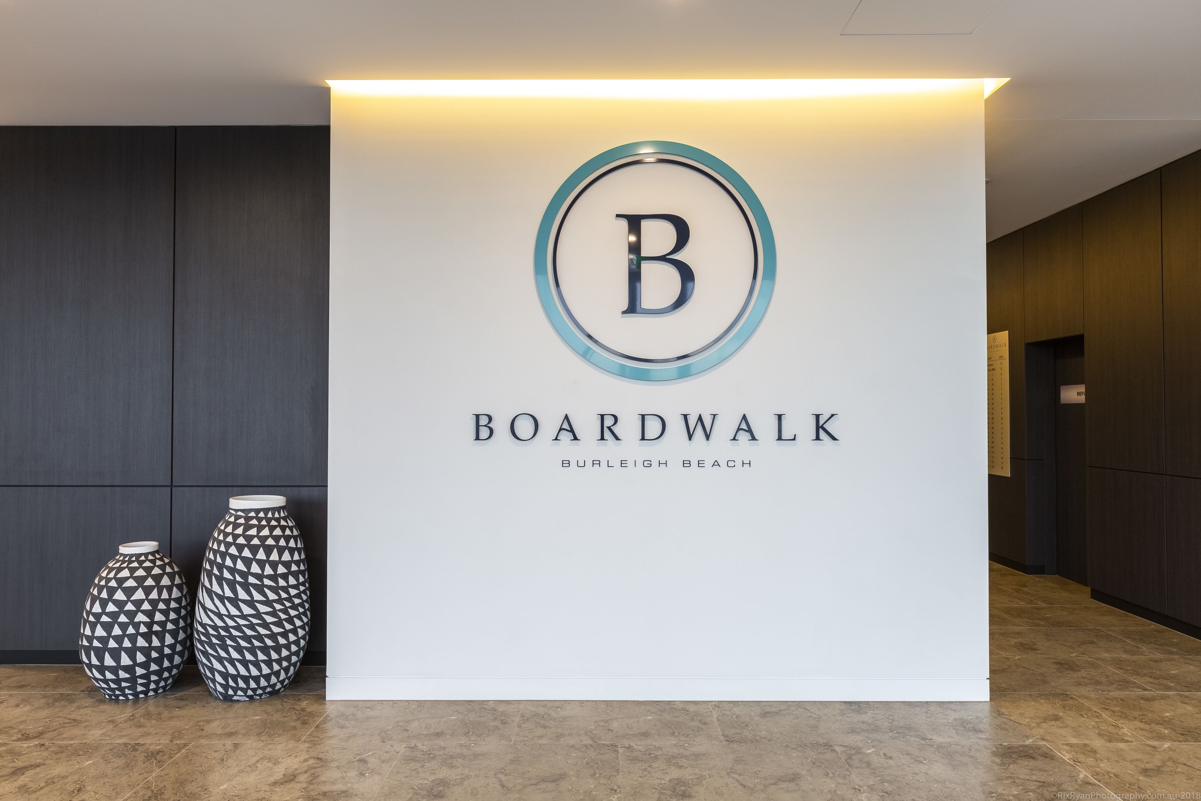 A reception desk with a logo, the name 'Boardwalk Burleigh Beach', and two patterned vases.