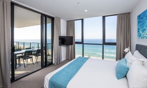 A hotel room with a large bed, a TV, and a balcony with a view of the ocean. - Boardwalk Burleigh Beach (Burleigh Heads)