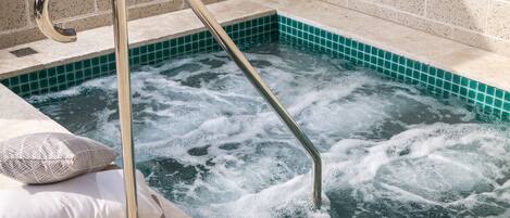 A spa pool with a metal ladder and two pillows on the edge.