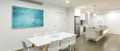 A modern kitchen with a central island, white cabinetry, and a stainless steel refrigerator.