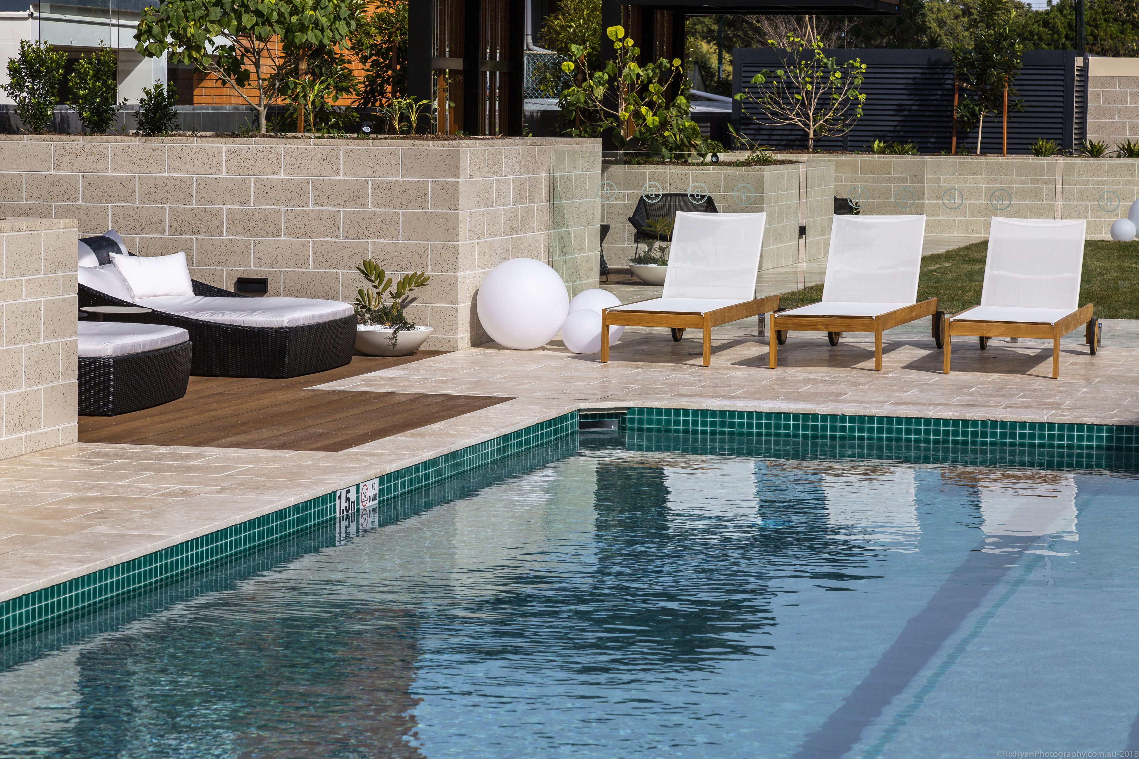 A poolside area with lounge chairs and a small garden.