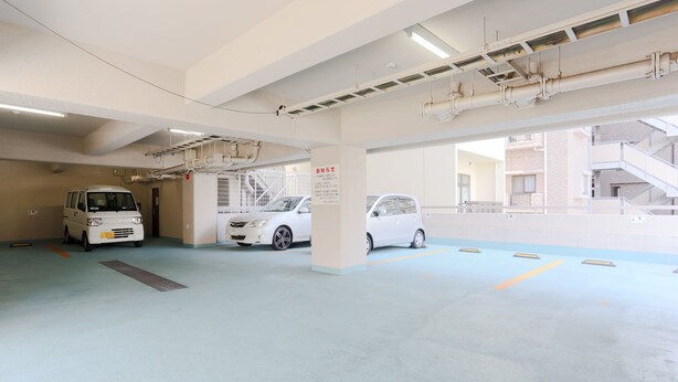 A parking garage with multiple levels, concrete floors, and overhead lighting.