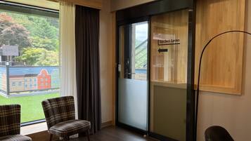 A hotel room with a view of a garden, a sliding door to the garden, and a sign indicating the garden's name.