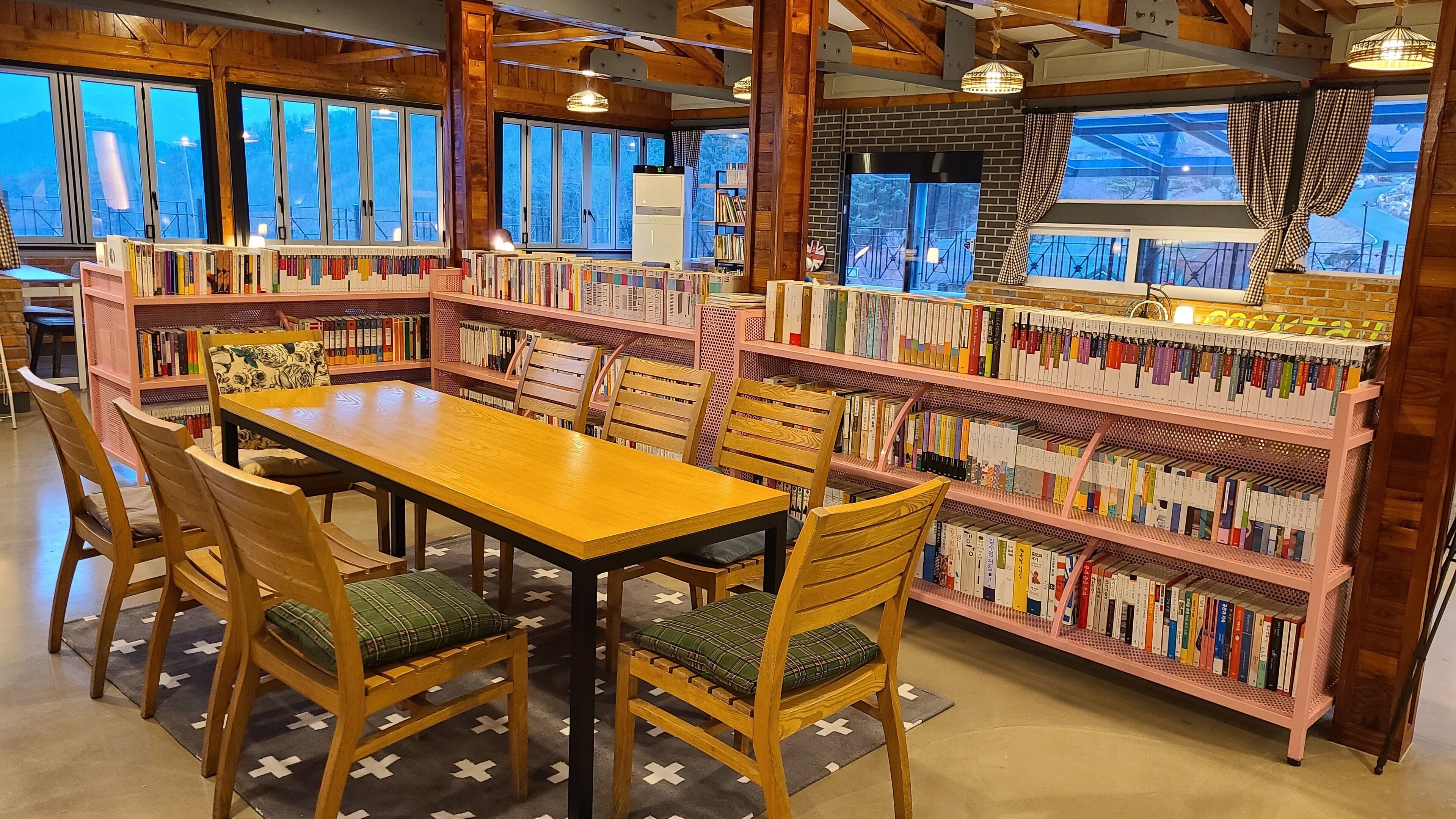 Una biblioteca con estanterías de madera, una mesa y sillas de madera.