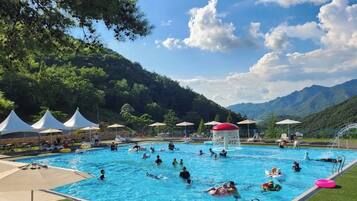 Una piscina al aire libre de temporada, sombrillas, tumbonas
