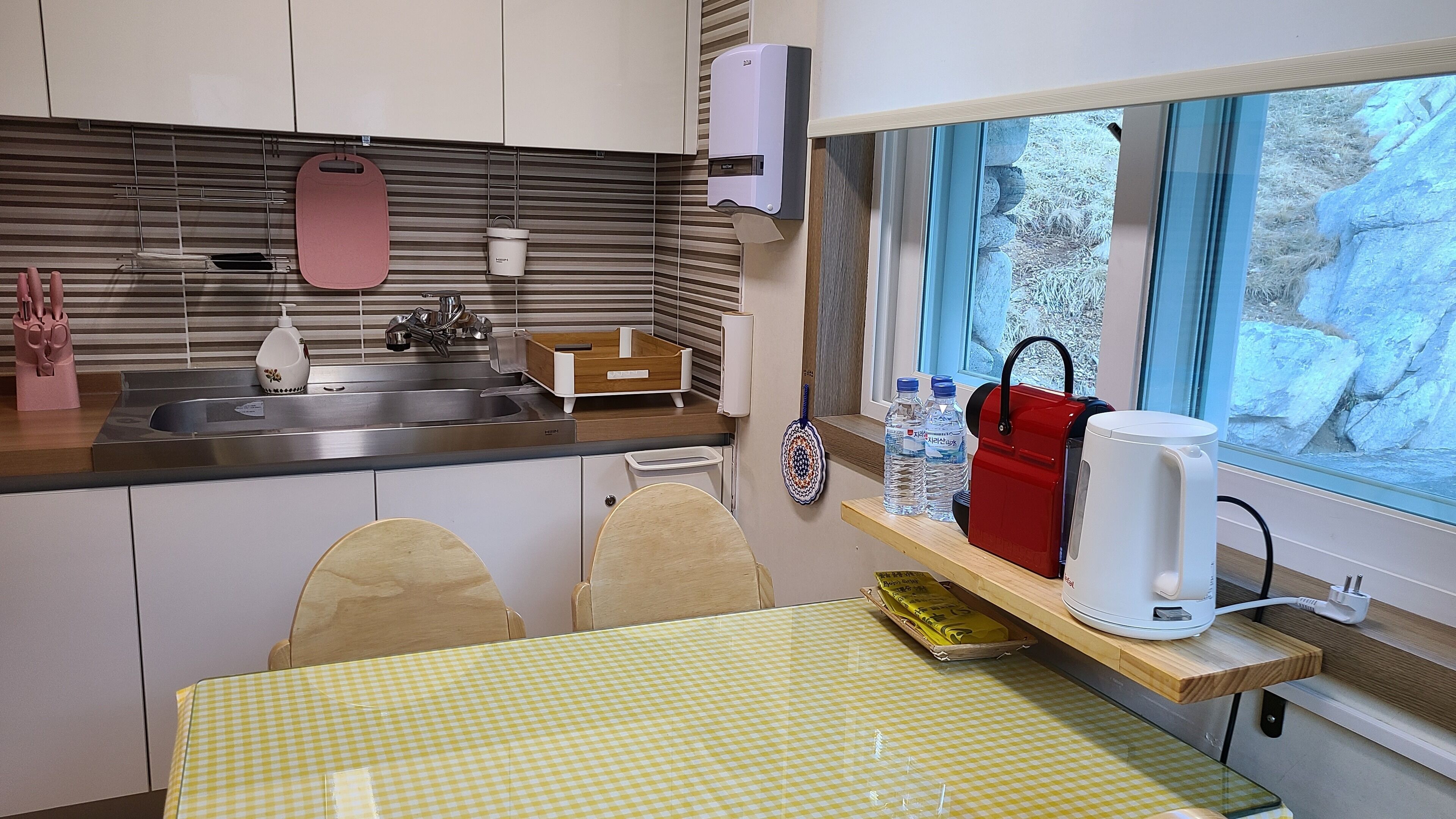 A compact kitchen with a sink, a kettle, and a window overlooking a snowy landscape.