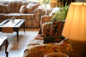 A living room with striped sofas, a coffee table, and a floral-patterned armchair.