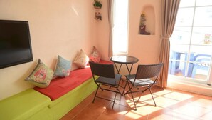 A room with a sofa, two chairs, a small table, a TV, and a window with curtains. - Galilee Bed and Breakfast (Hengchun)