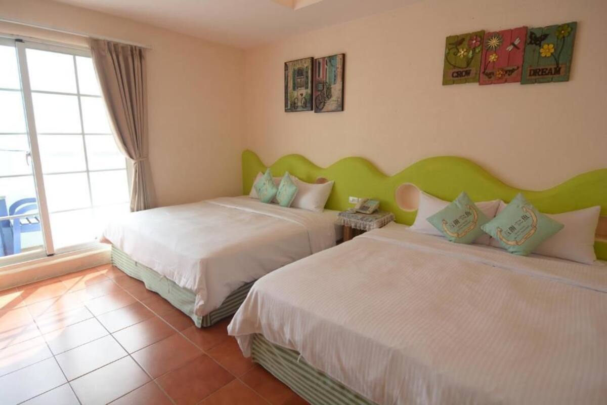 Habitació d'hotel amb dos llits, una porta corredissa de vidre i obra d'art a les parets.