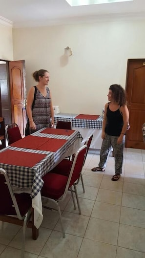 A dining area with checkered tablecloths and red chairs. - Paula Guest House (Gulu)