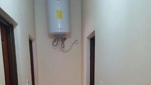 Un pasillo estrecho con suelo de baldosas y un equipo de aire acondicionado blanco instalado en la pared.