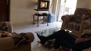 Una sala de estar con sofá, sillones, una mesa de centro, televisor y ventana con vistas.