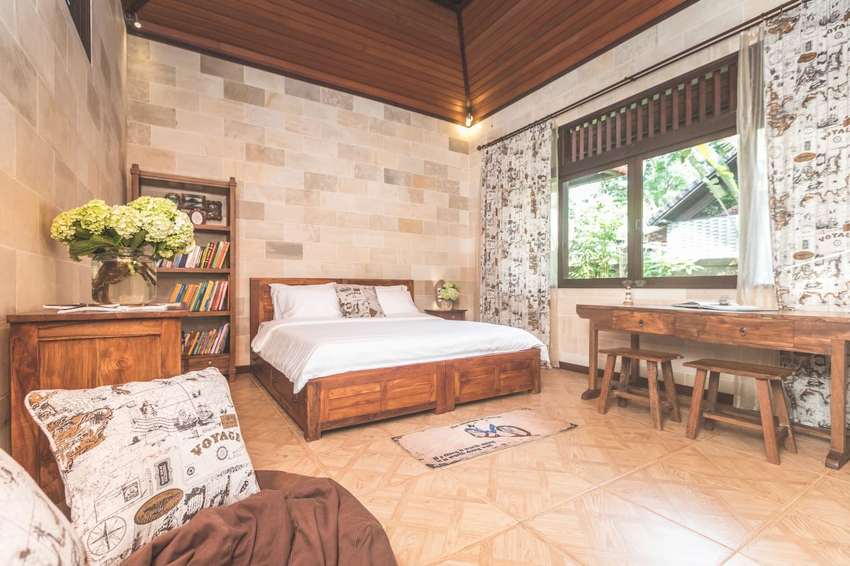 A bedroom with a wooden bed, a desk, and a bookshelf.