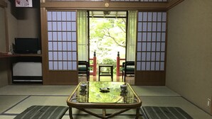 A traditional Japanese room with tatami flooring, a low table with a glass top, and sliding doors leading to a garden. - Koyasan Sekishoin (Koya)