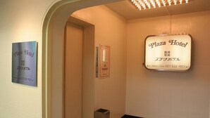 Un pasillo con un letrero que indica el Hotel Plaza, entrada principal 3F y un número de contacto.