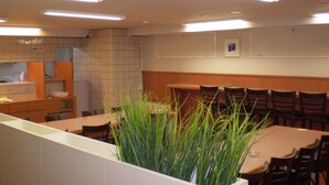 Un restaurante con una barra larga, varias sillas y una maceta grande con plantas verdes en el centro.