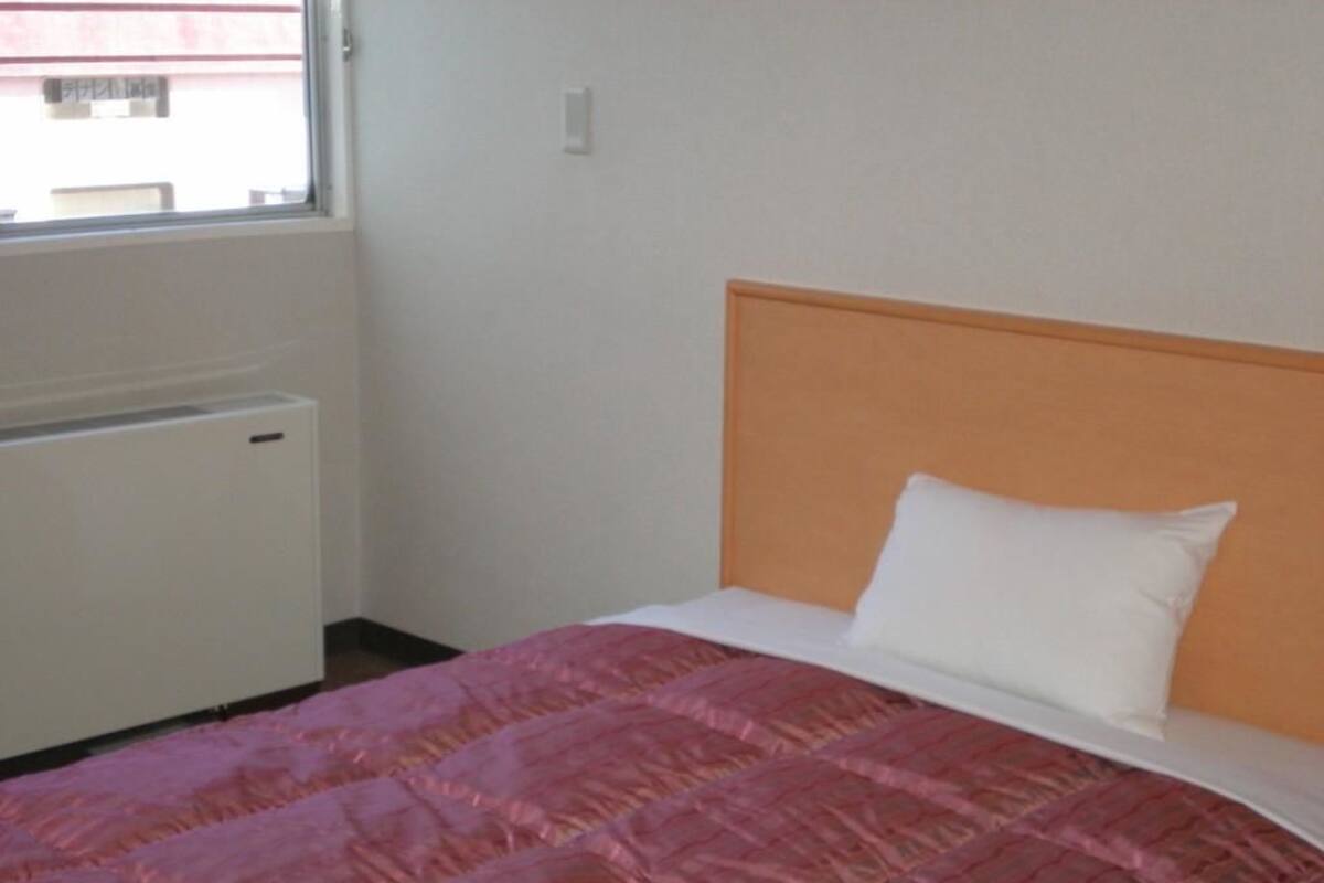 Un dormitorio con una cama, una ventana y un radiador.