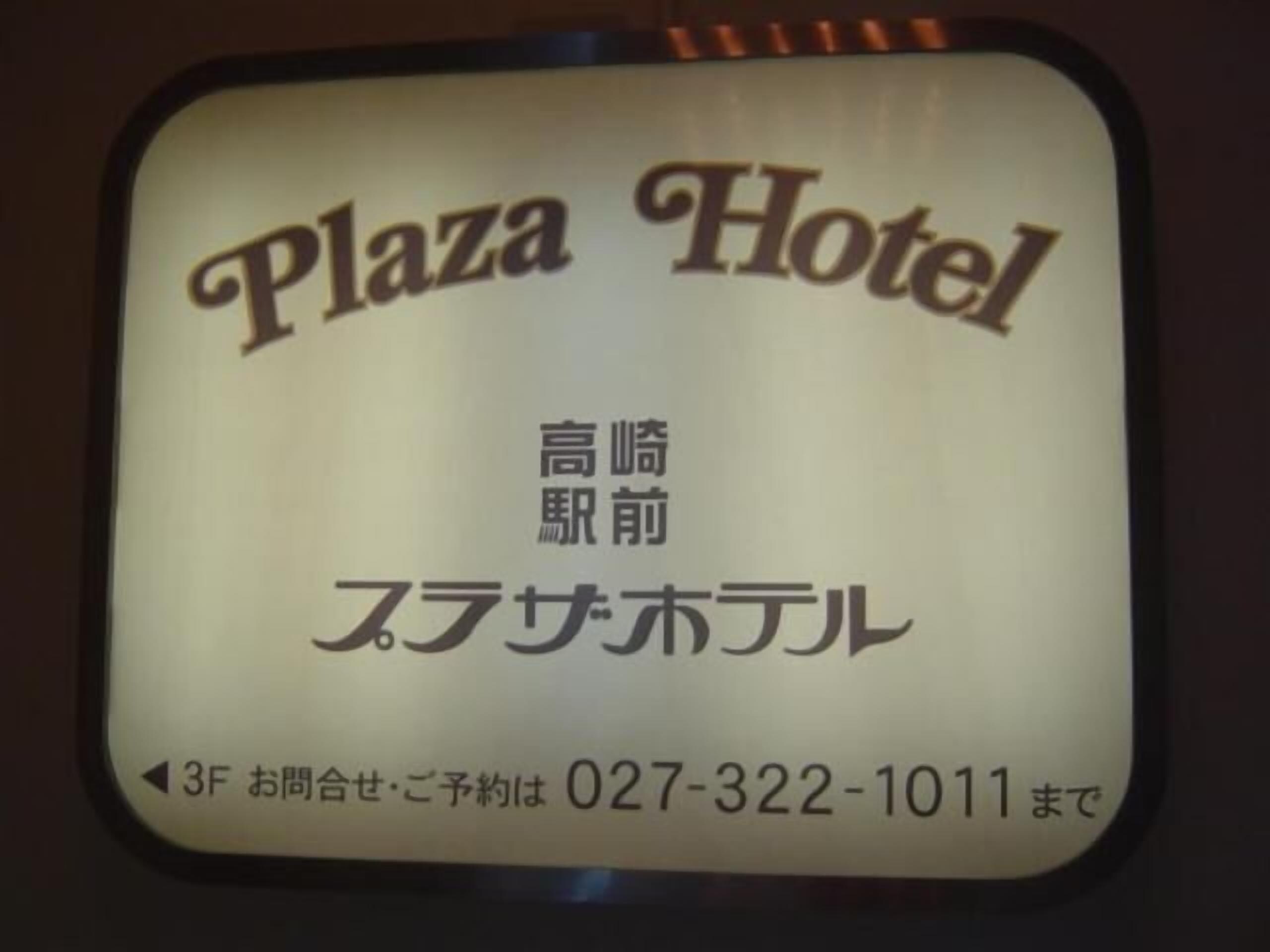 Señal del Hotel Plaza con texto en japonés y un número de teléfono.