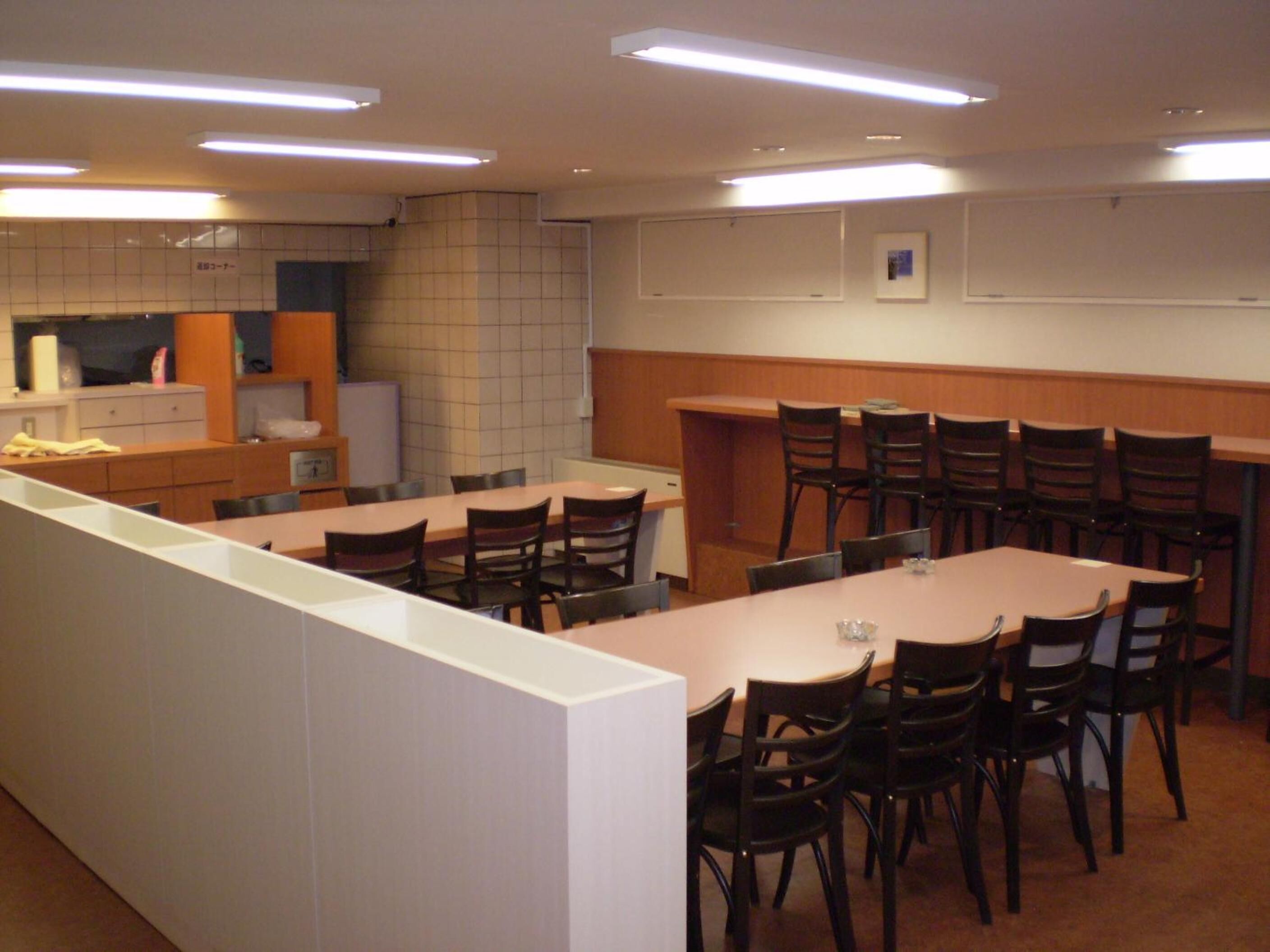 A conference room with a long table and chairs, a kitchenette area, and a whiteboard on the wall.