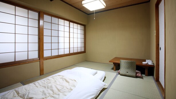 Una habitación japonesa tradicional con suelo de tatami, un escritorio de madera bajo y una puerta corredera de shoji.