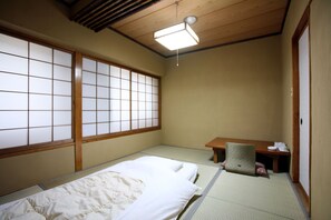 Una habitación japonesa tradicional con suelo de tatami, un escritorio de madera bajo y una puerta corredera de shoji.