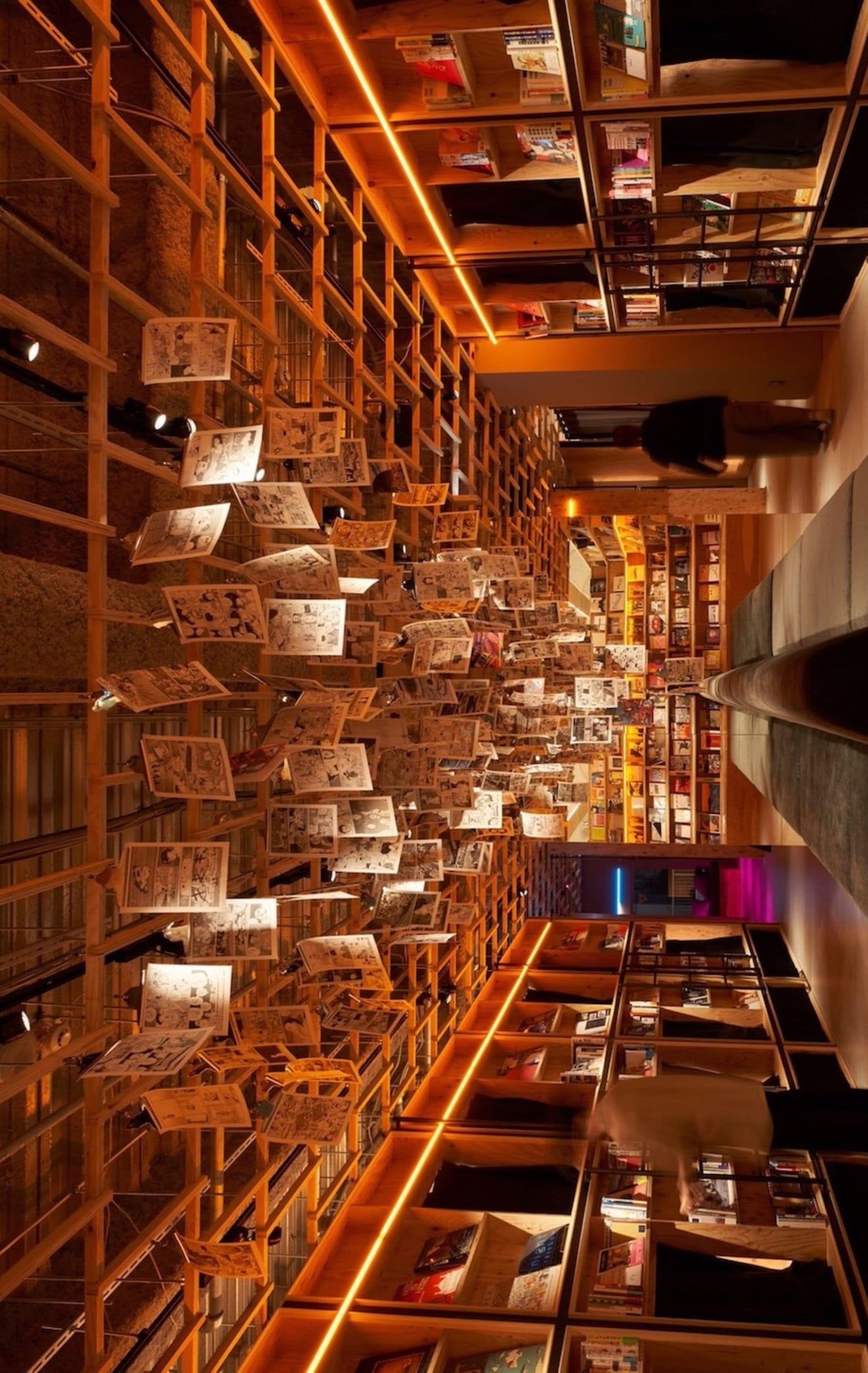 Una biblioteca con scaffali colmi di libri e riviste, scaffali in legno e un'ampia corsia centrale.