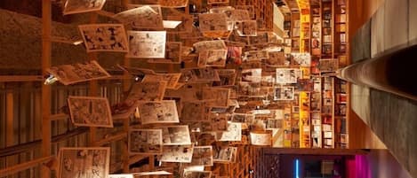 A library with bookshelves filled with books and magazines, wooden bookshelves, and a central aisle.