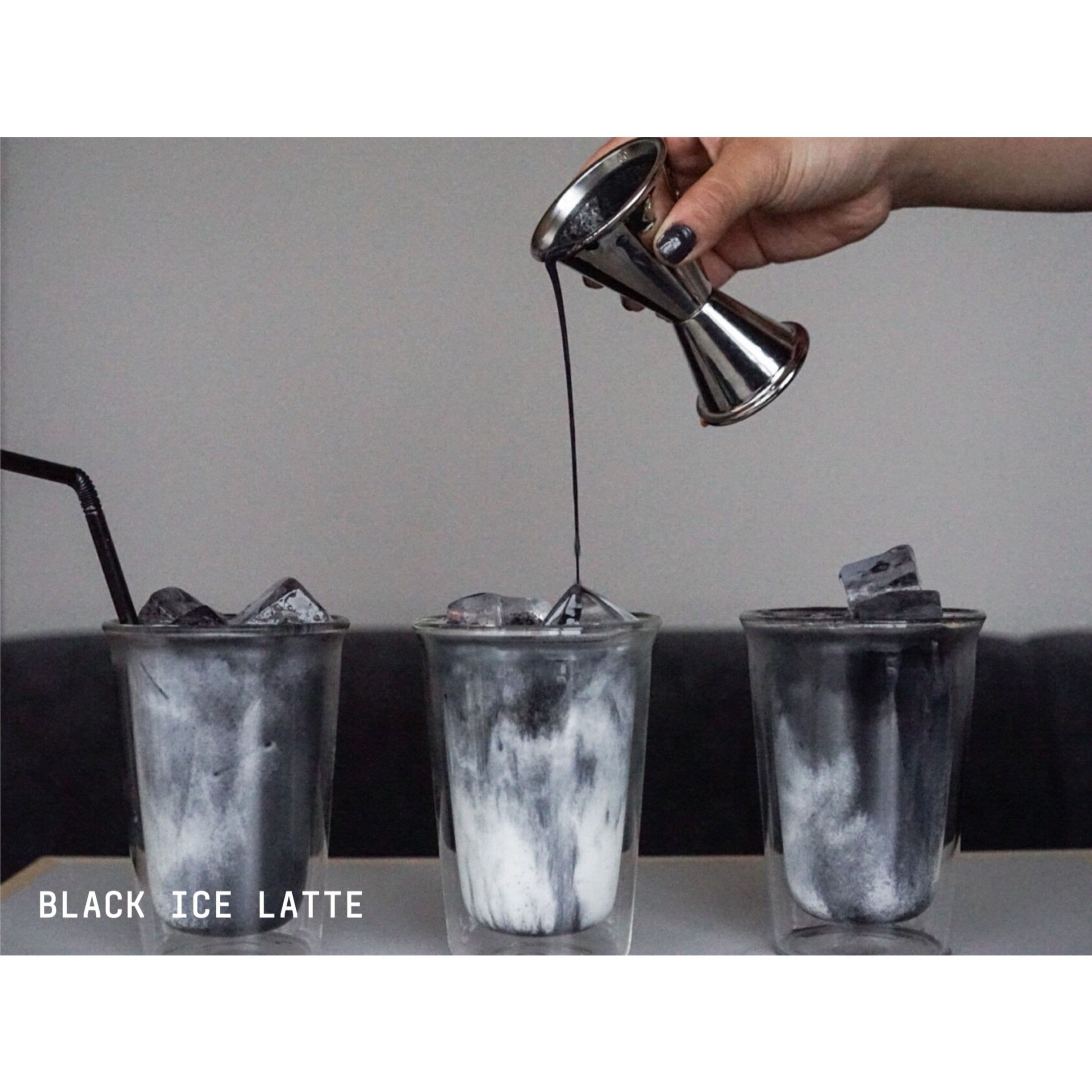 Three glasses of black ice latte with ice cubes, one being filled with a dark liquid from a metal jigger.