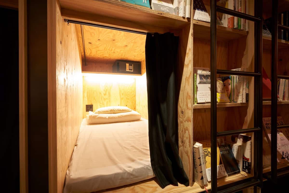 A compact room with a bunk bed, a small desk, and a bookshelf filled with books.