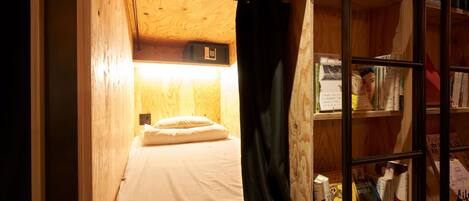 A compact room with a bunk bed, a small desk, and a bookshelf filled with books.