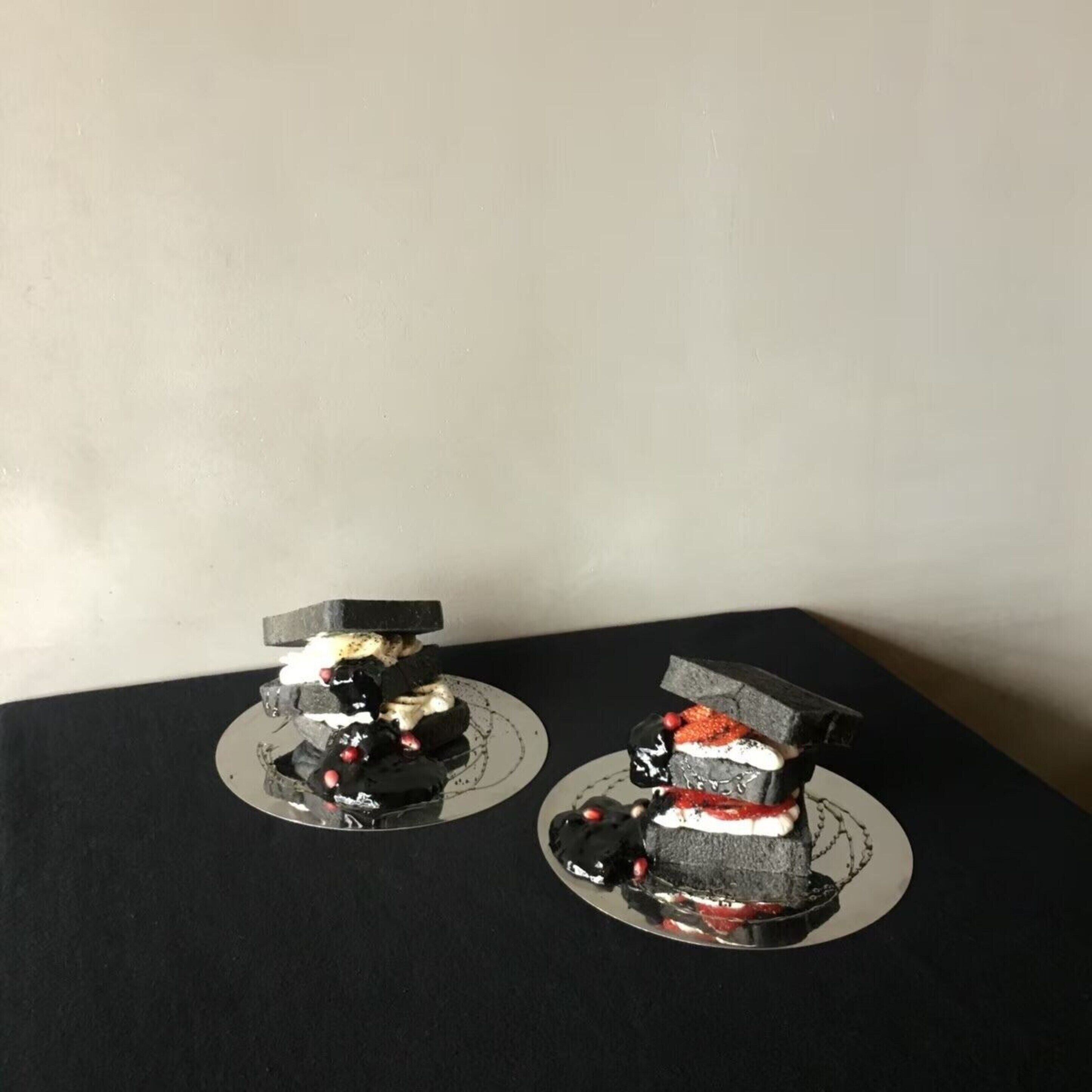 Deux gâteaux présentés sur des assiettes noires, avec un fond uni.