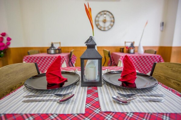 A dining table set with two plates, cutlery, and a candle in a lantern. - Phurua Inn (Phu Ruea)