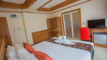 Una habitación de hotel con cama, escritorio, televisor y armario.
