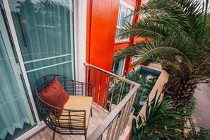 A balcony with a wicker chair, a small table, and a potted plant.