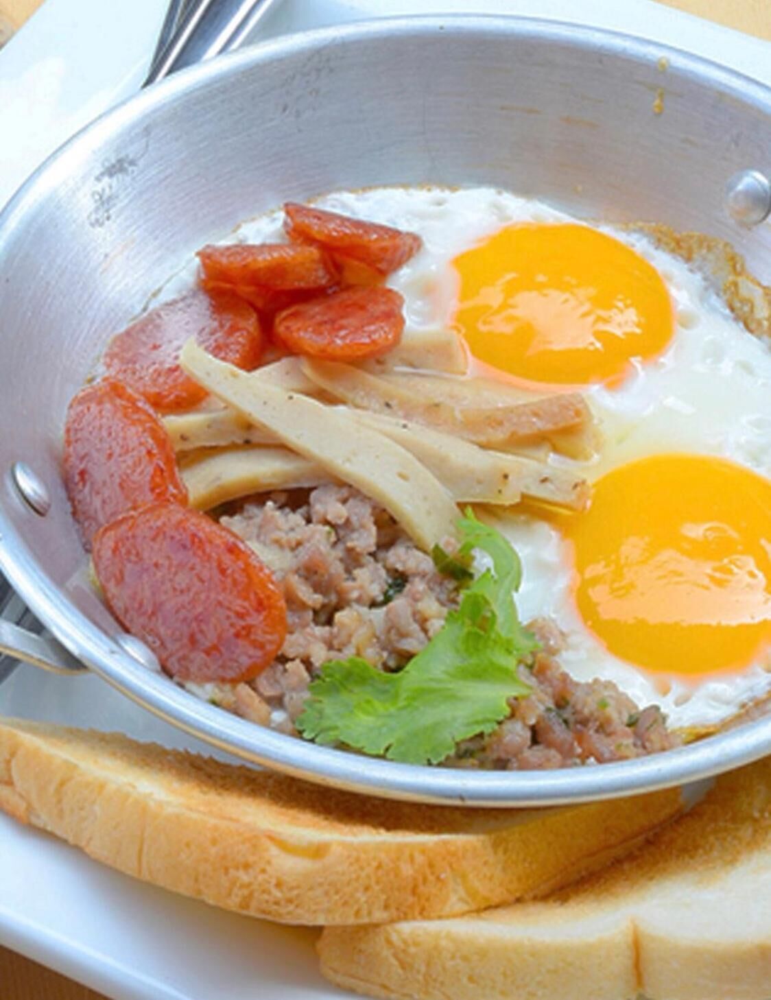 Un plato de desayuno con huevos, salchicha y pan.