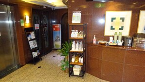 Eine Hotelhalle mit einer Rezeption, einem Automaten und einem Regal mit Pflegeprodukten.