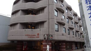Ein modernes Hotel mit einer markanten, wellenförmigen Fassade, mehreren Balkonen und einem gut sichtbaren Eingangsbereich mit Fahrradstellplätzen.