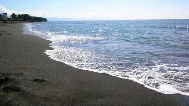 A beach with a sandy shore and waves gently lapping at the edge.