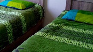 Two single beds with wooden headboards and green bedding with a geometric pattern.