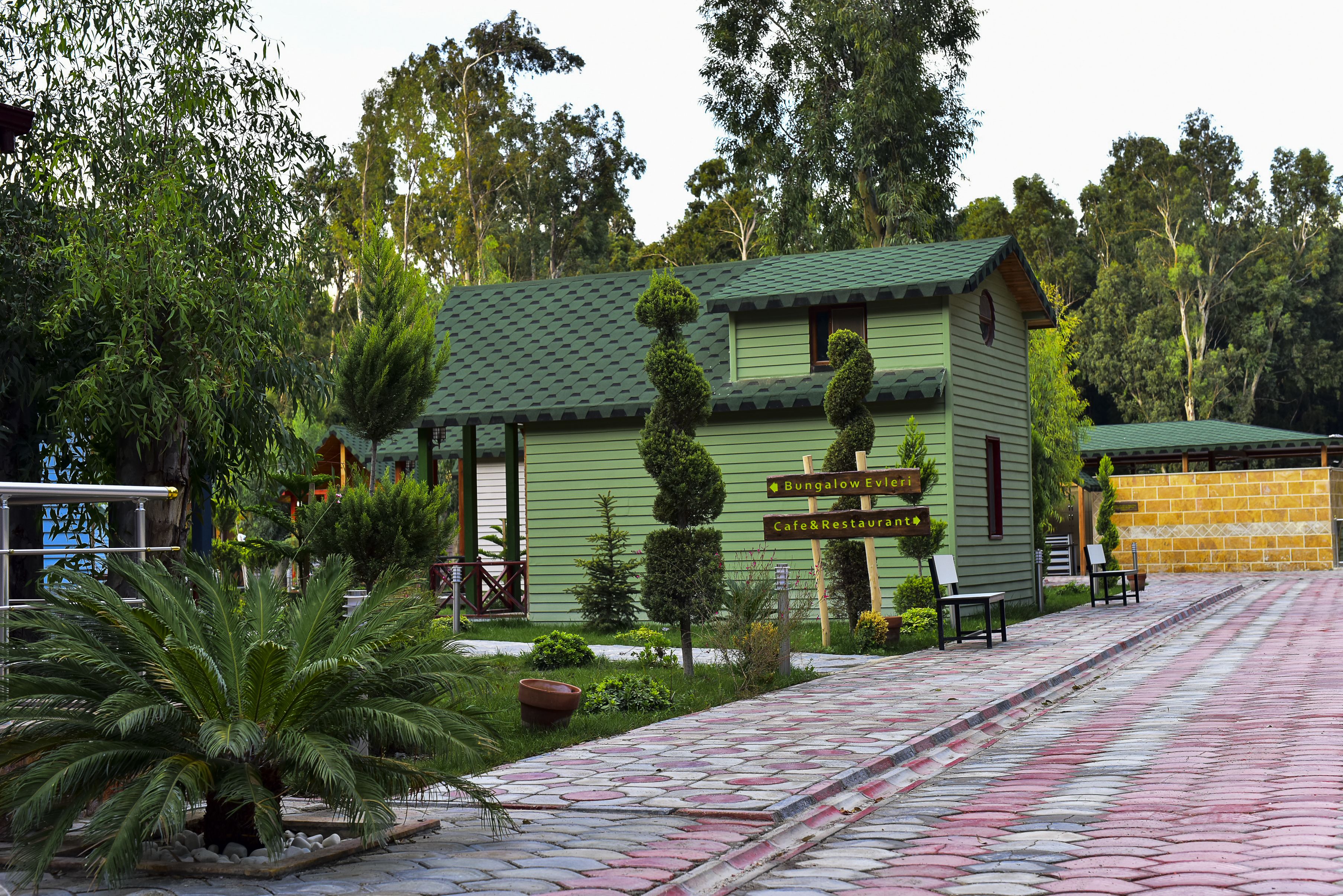 A green bungalow with a sign indicating a bungalow, cafe, and restaurant.