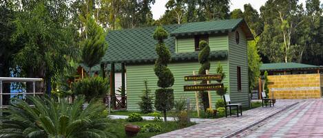 A green bungalow with a sign indicating a bungalow, cafe, and restaurant.
