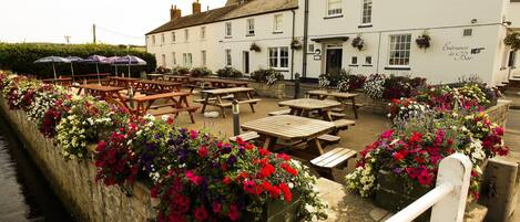 A riverside pub with outdoor seating and flower boxes.