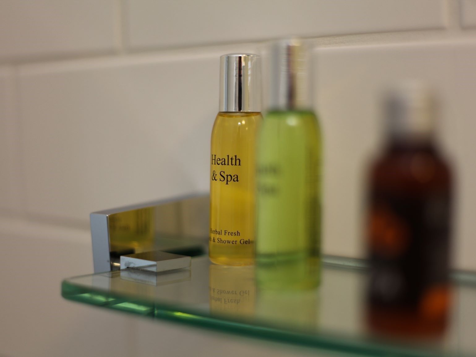 A bathroom shelf with three bottles of health and spa products.