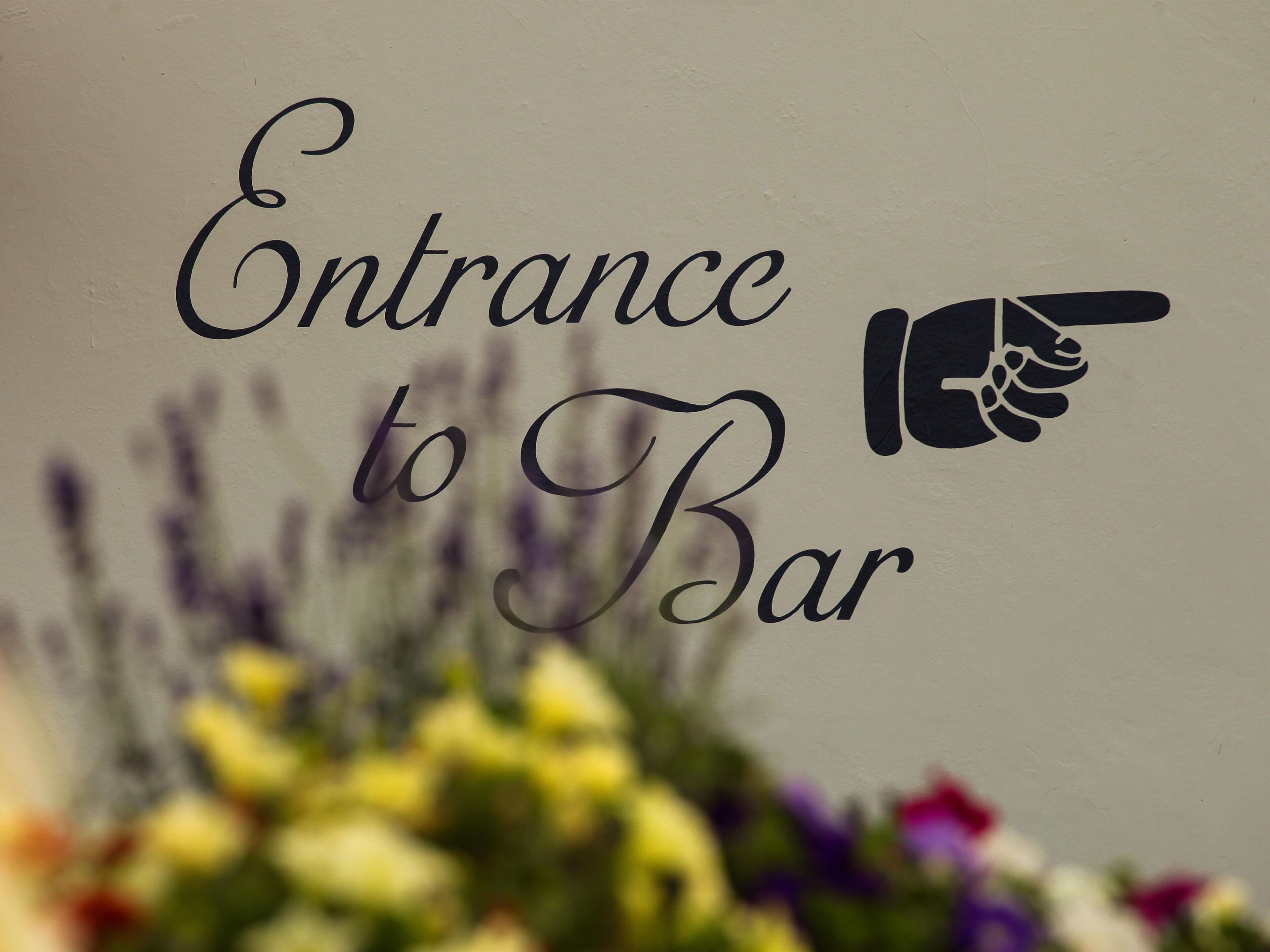 A sign with the text "Entrance to Bar" and a pointing hand icon.