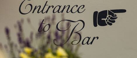 A sign with the text "Entrance to Bar" and a pointing hand icon.