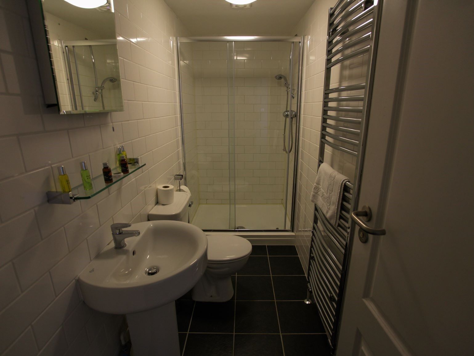 A modern bathroom with a glass-enclosed shower, a white sink, and a toilet.