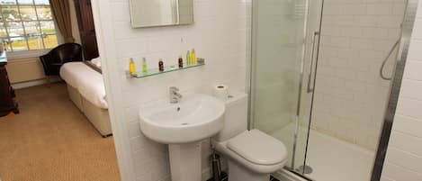 A bathroom with a toilet, sink, and glass shower enclosure.