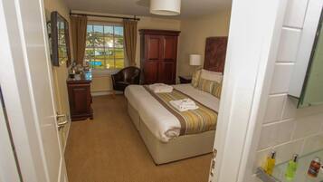 Ein Hotelzimmer mit Bett, Schreibtisch, Stuhl, Fenster mit Blick und einem Badezimmer mit Pflegeartikeln.