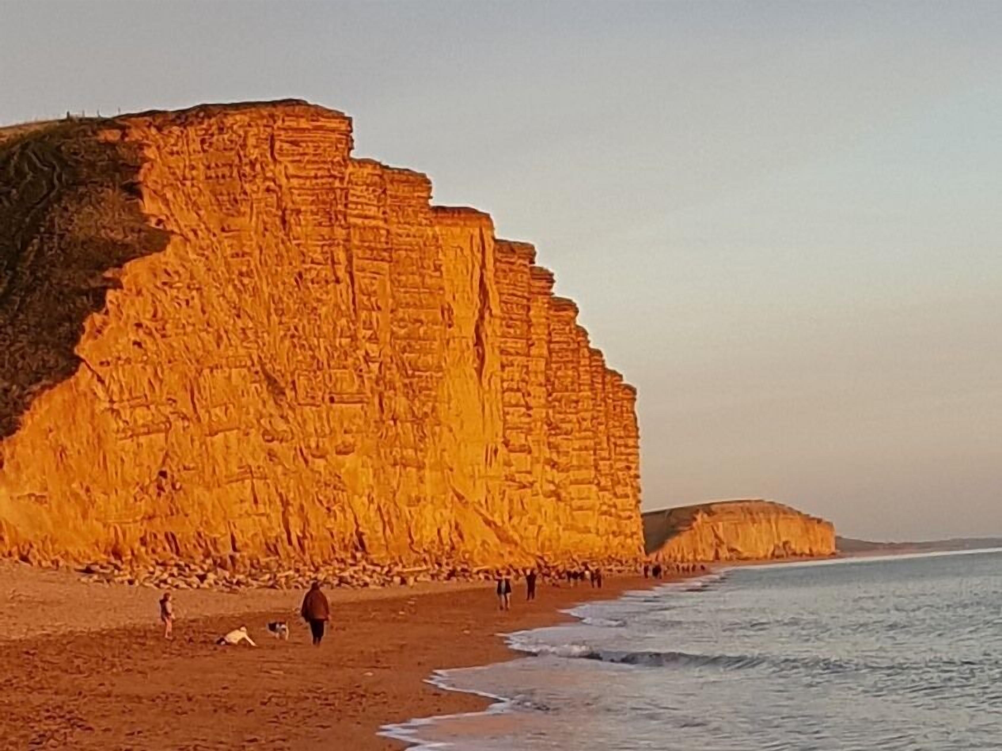 Una playa costera con grandes acantilados escalonados y una orilla arenosa.