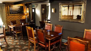 Un restaurante con mesas y sillas de madera, un menú en una pizarra y un espejo en la pared.